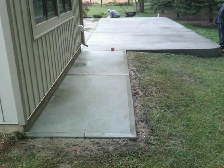 Concrete patio next to a house. A larger patio area in the background.
