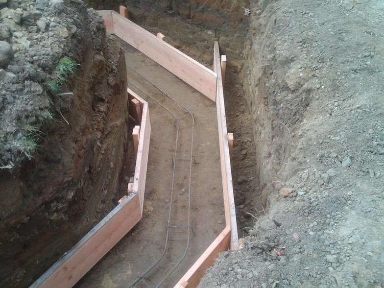 Wooden forms in an excavated trench for a concrete structure, with rebar visible.