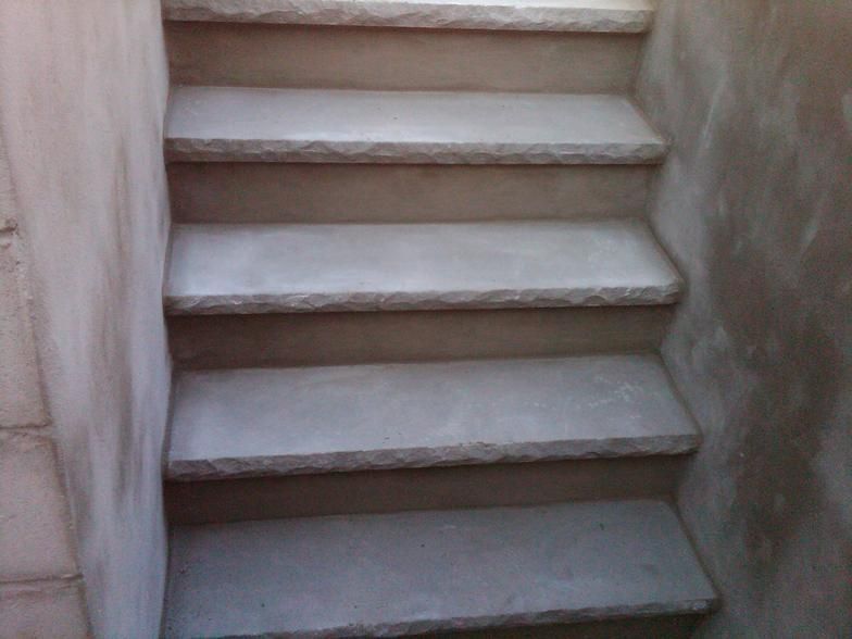 Concrete stairs descending, surrounded by light-colored walls.
