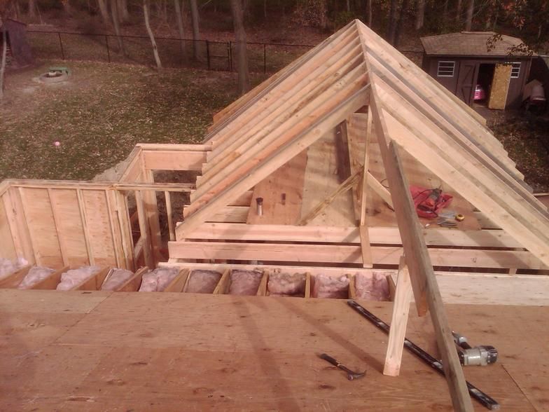 Construction of a wooden roof frame. Building materials and tools are visible.