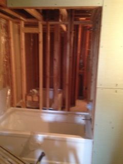 A partially constructed bathroom with a white bathtub in a wooden frame.