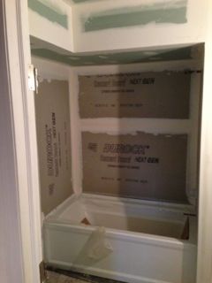 A tub and shower alcove under construction, featuring cement board walls and drywall.