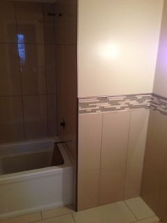 Bathroom with a bathtub, tan tile walls, and a decorative border.