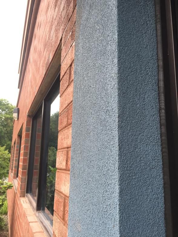 Brick building with blue textured column beside black-framed windows.