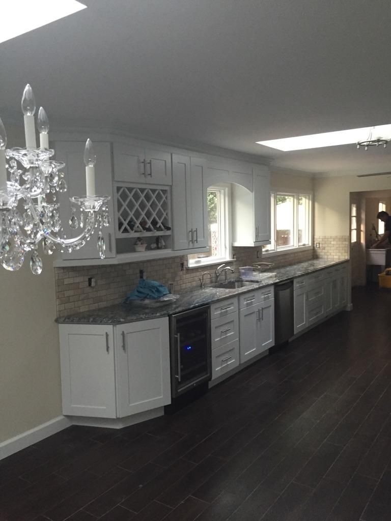 White kitchen cabinets with dark wood floors and a crystal chandelier.