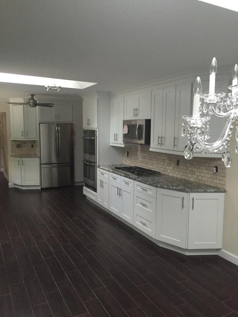 White kitchen with dark wood floors, stainless steel appliances, and granite countertops.