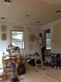 Person painting a room with paint swatches on the wall; interior shot.