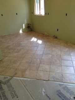 Room with newly tiled beige floor; light green walls; unfinished window; building project.