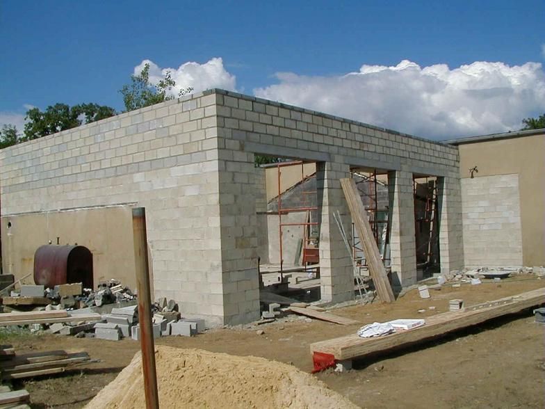 Building under construction: concrete block structure with unfinished windows and a pile of sand in the foreground.