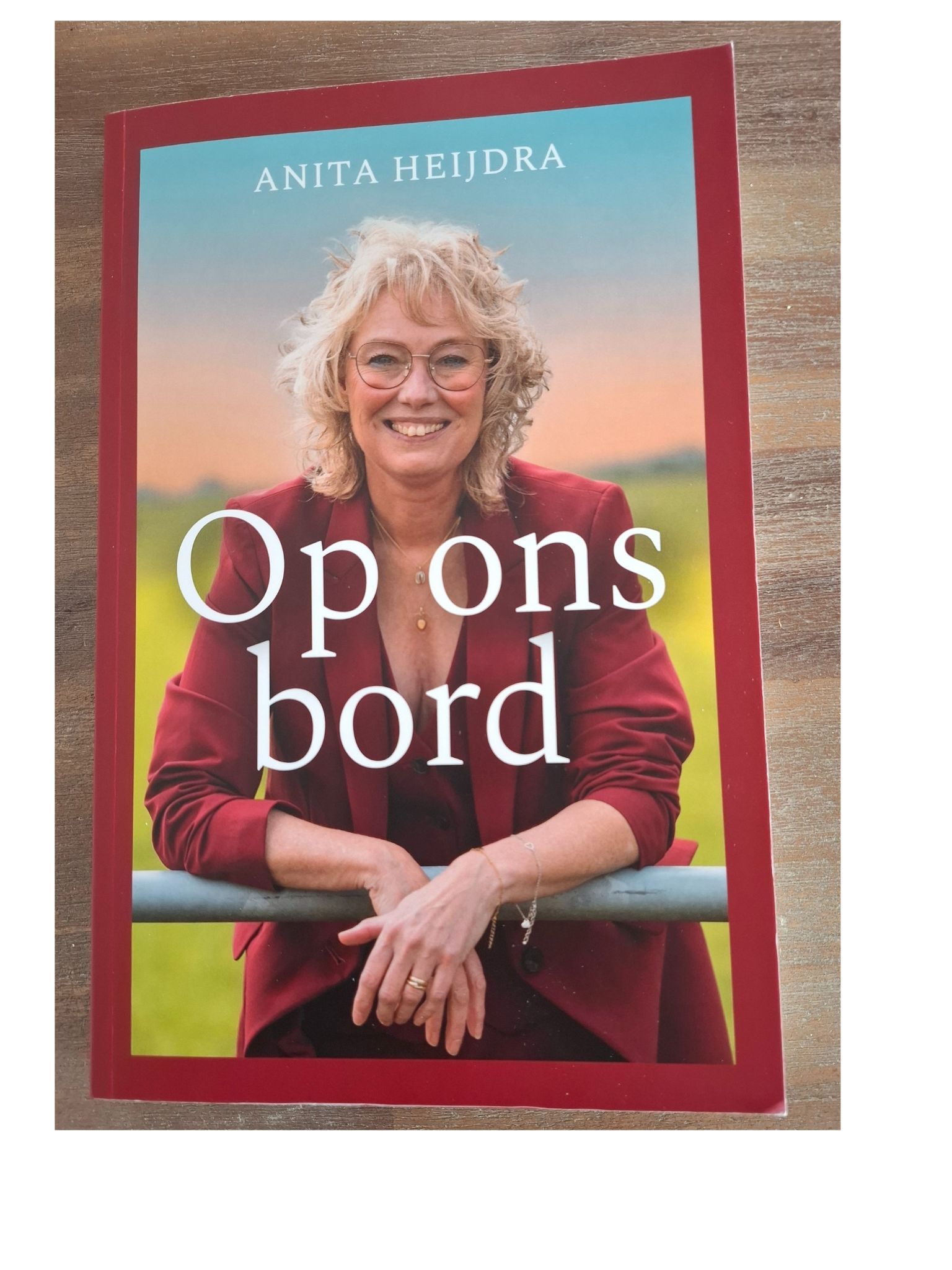 Boekomslag: Anita Heijdra lacht, gekleed in een rood jasje met de tekst