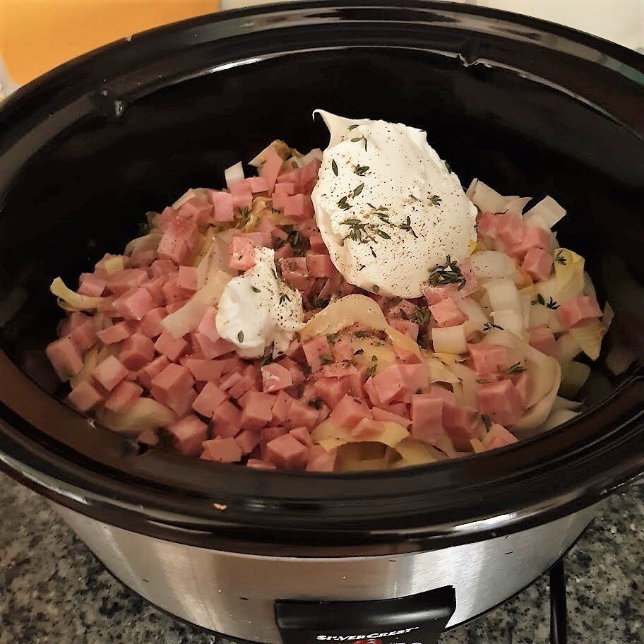 Een crockpot gevuld met ham, witlof en creme fraiche