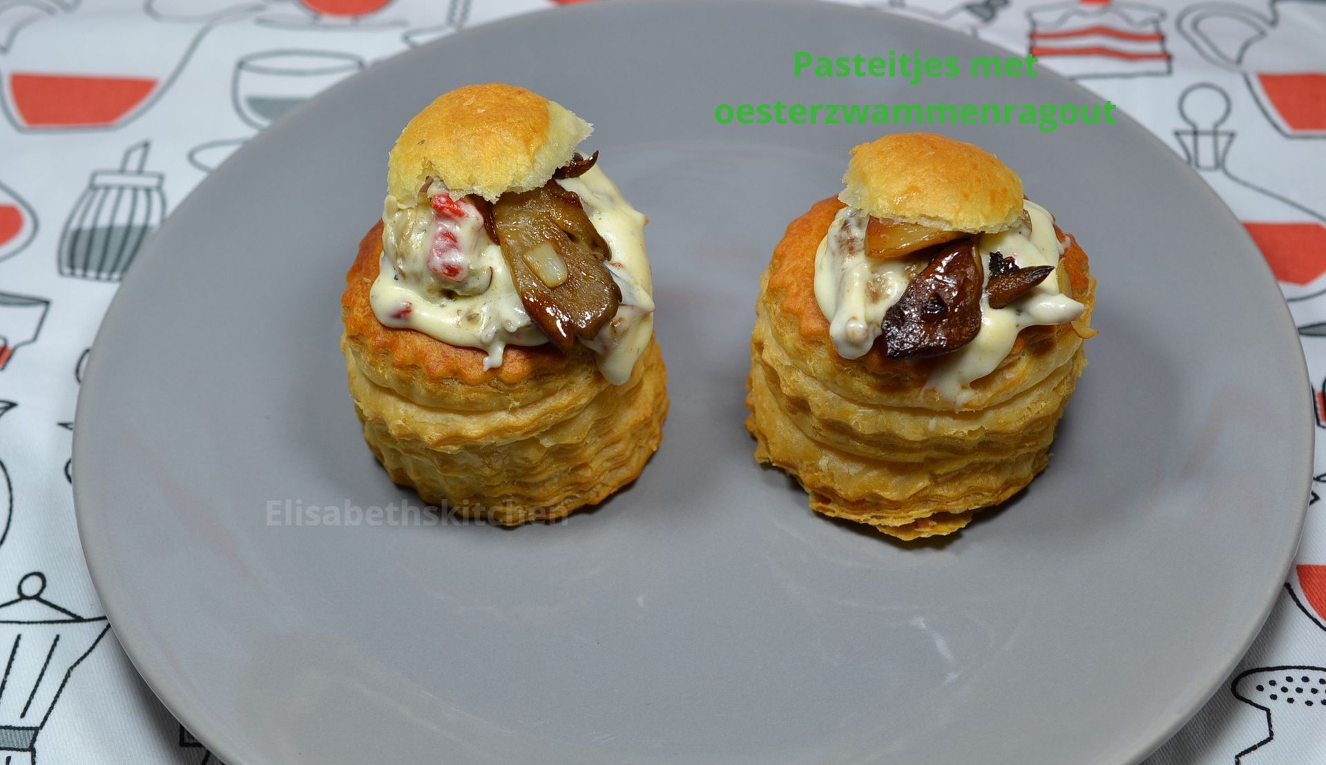 Twee pasteitjes gevuld met oesterzwamragout staan op een grijs bord op een tafel.