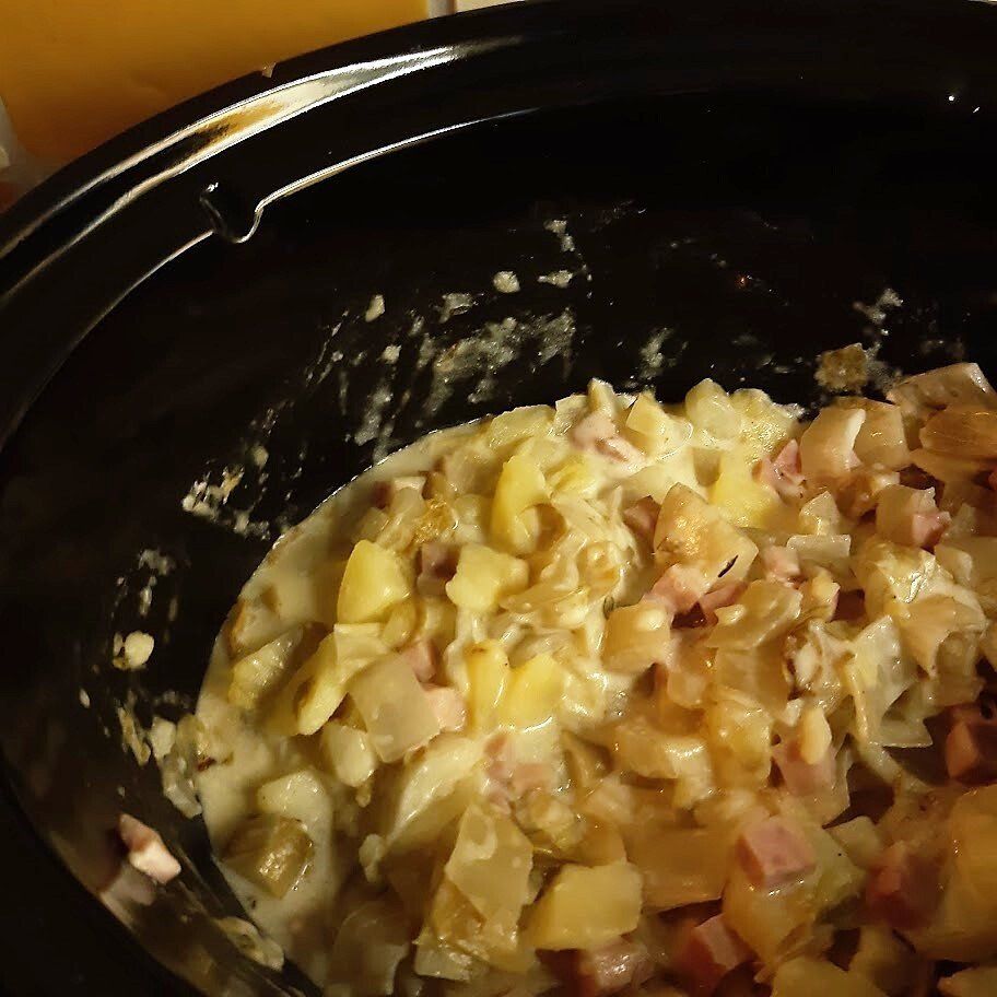 Een close-up van een crockpot gevuld witlof, ham en kaas