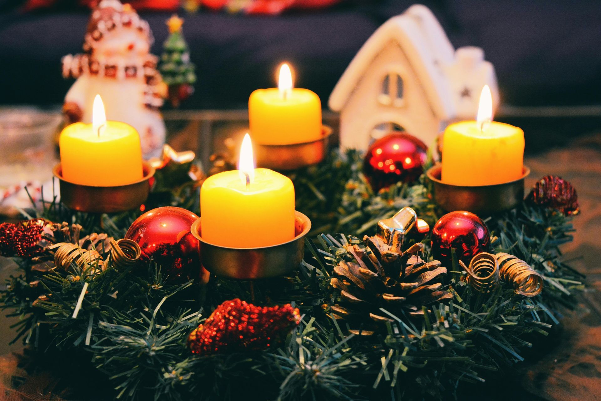 A christmas wreath with four candles and decorations on a table.