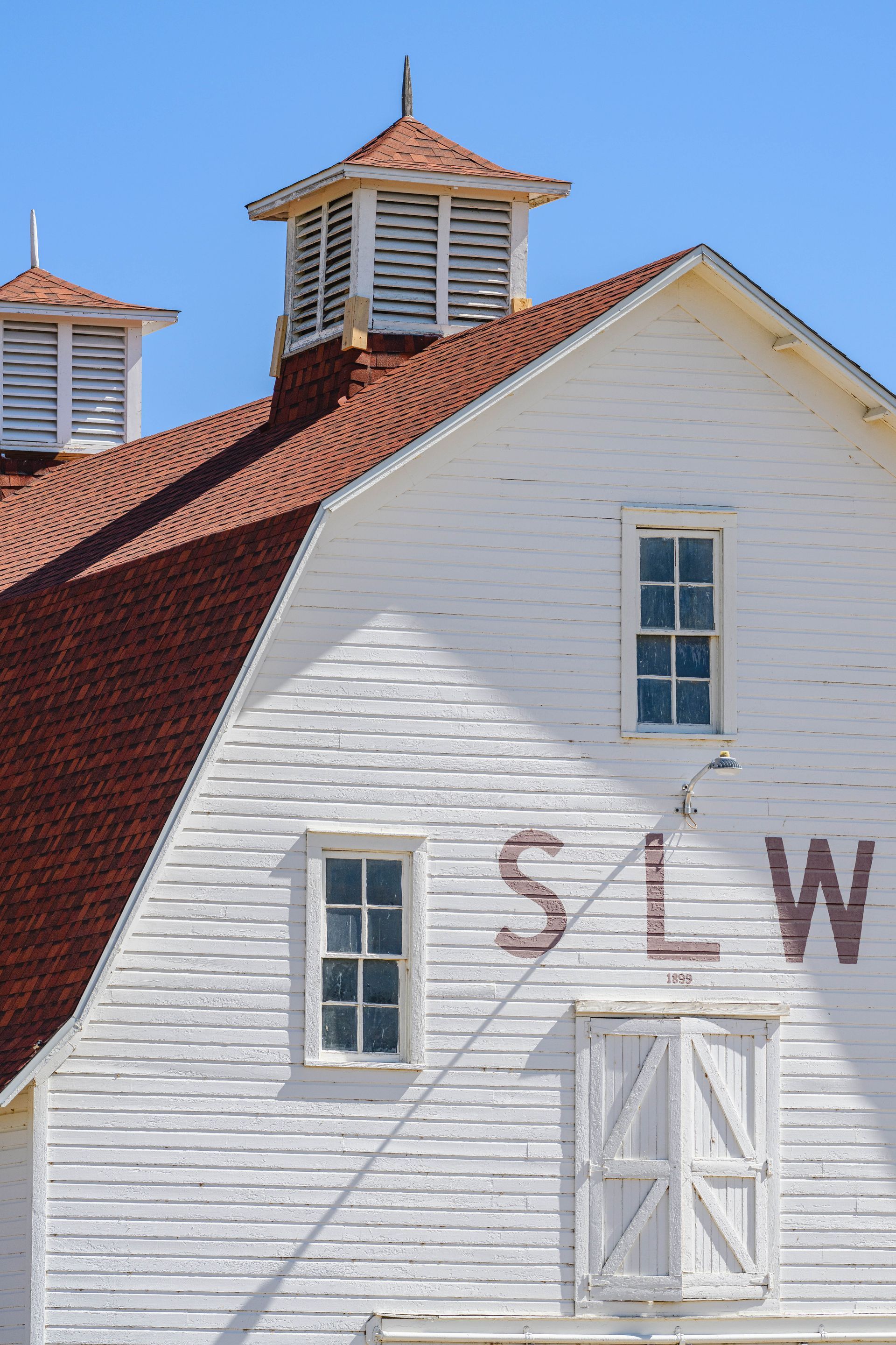 Exterior metal roof with brick chimneys, skylights, and durable roofing tiles under cloudy sky.