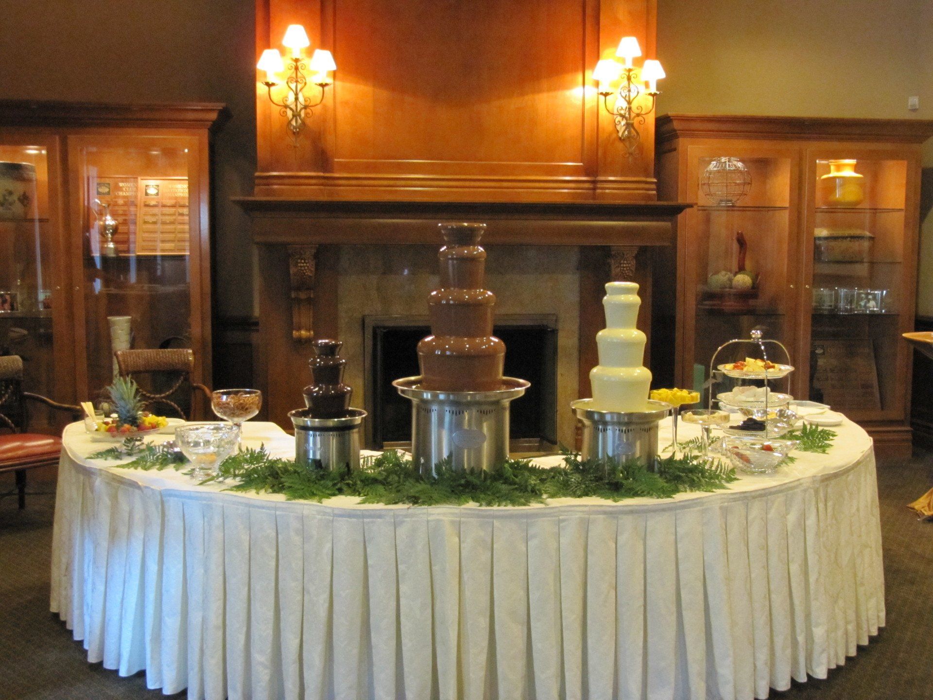A table with a chocolate fountain on it in front of a fireplace