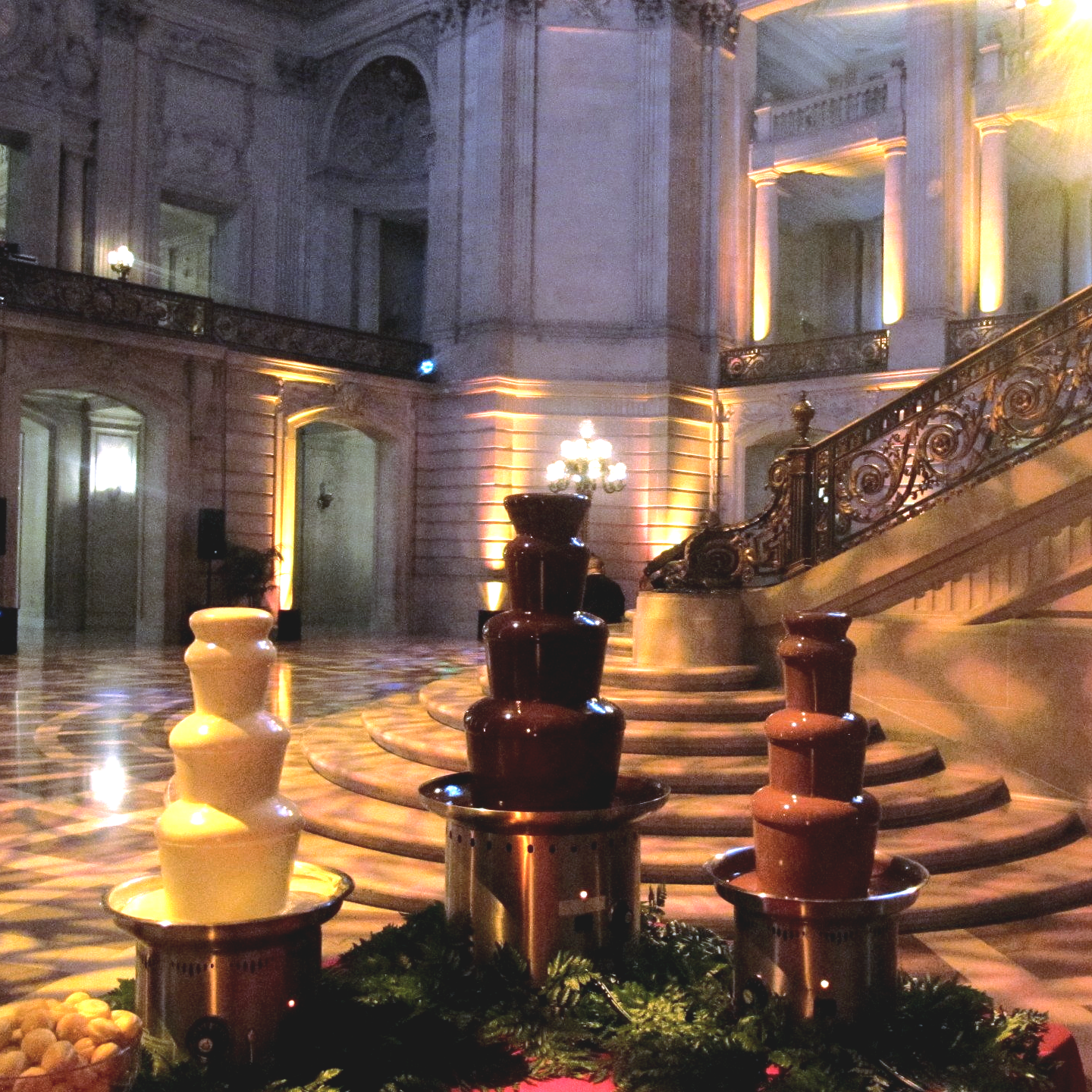 Several chocolate fountains in a large room with stairs