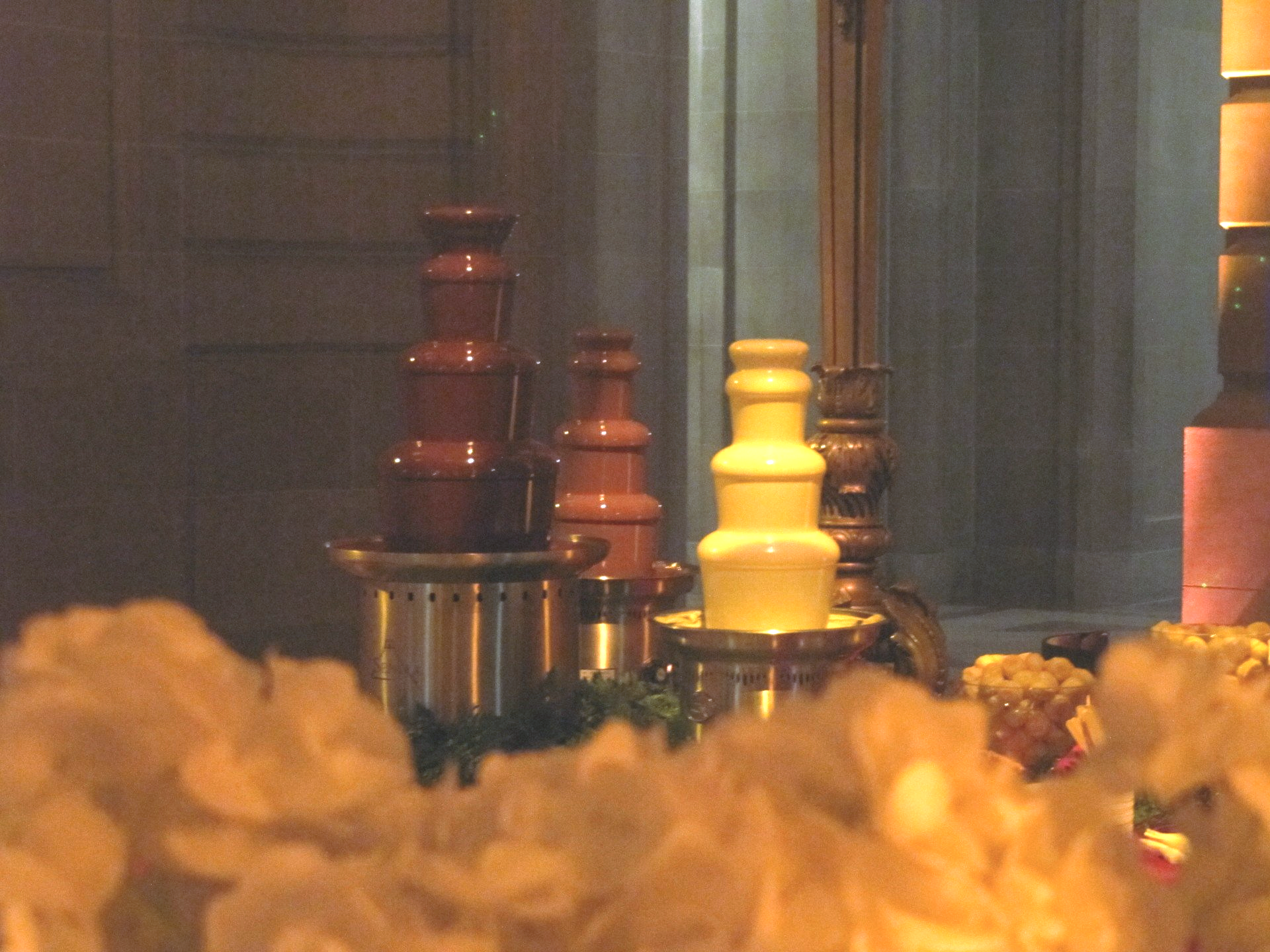 A row of chocolate fountains are lined up in a dark room