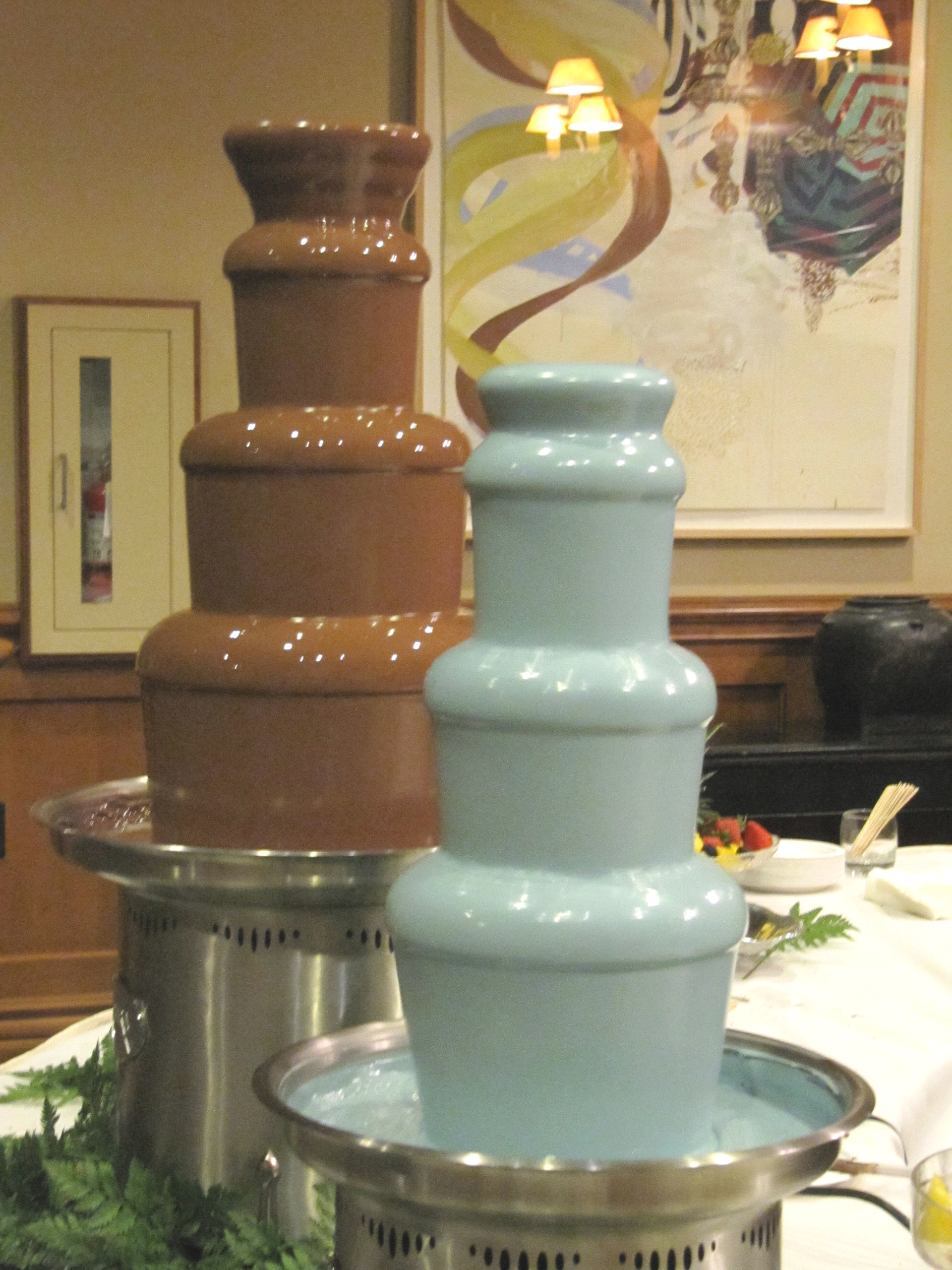 Two chocolate fountains are stacked on top of each other on a table