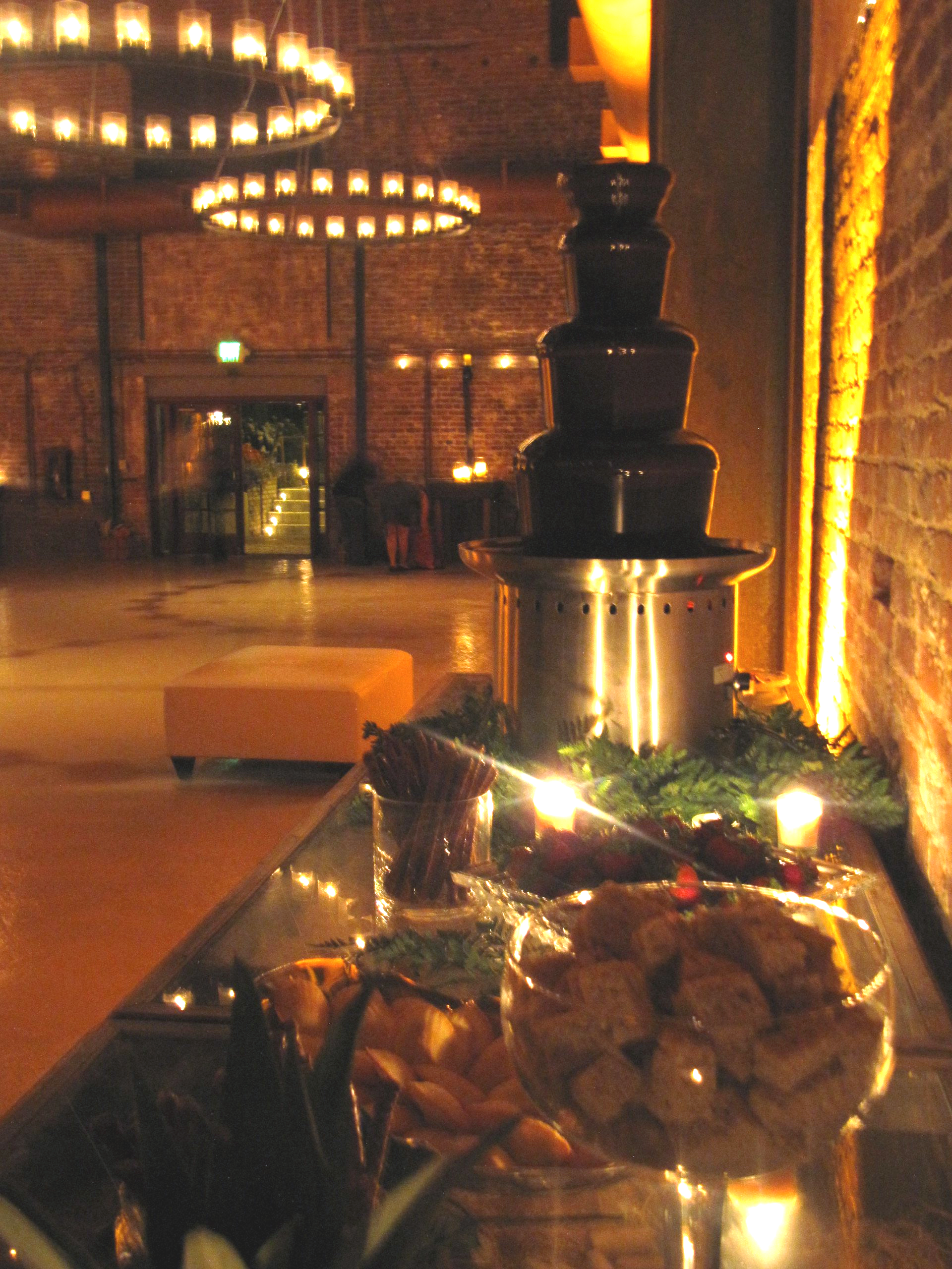 A chocolate fountain is lit up in a dark room
