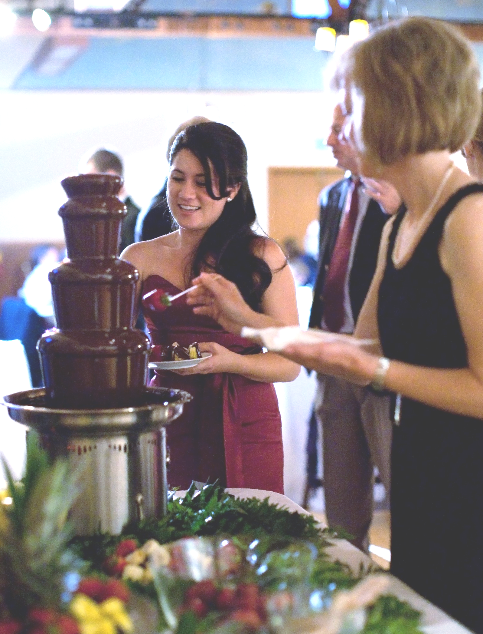A woman in a red dress is standing in front of a chocolate fountain