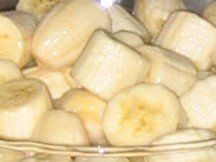 A glass bowl filled with sliced bananas on a table.