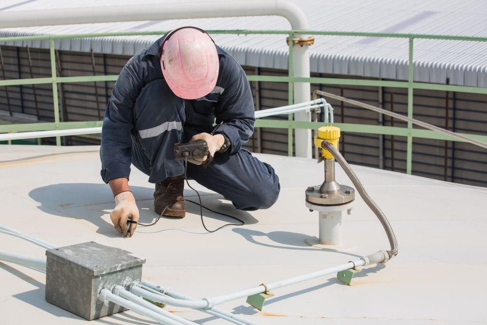 A Man is Kneeling Down on a Roof Working on a Pipe — Elite Water In Koonorigan, NSW
