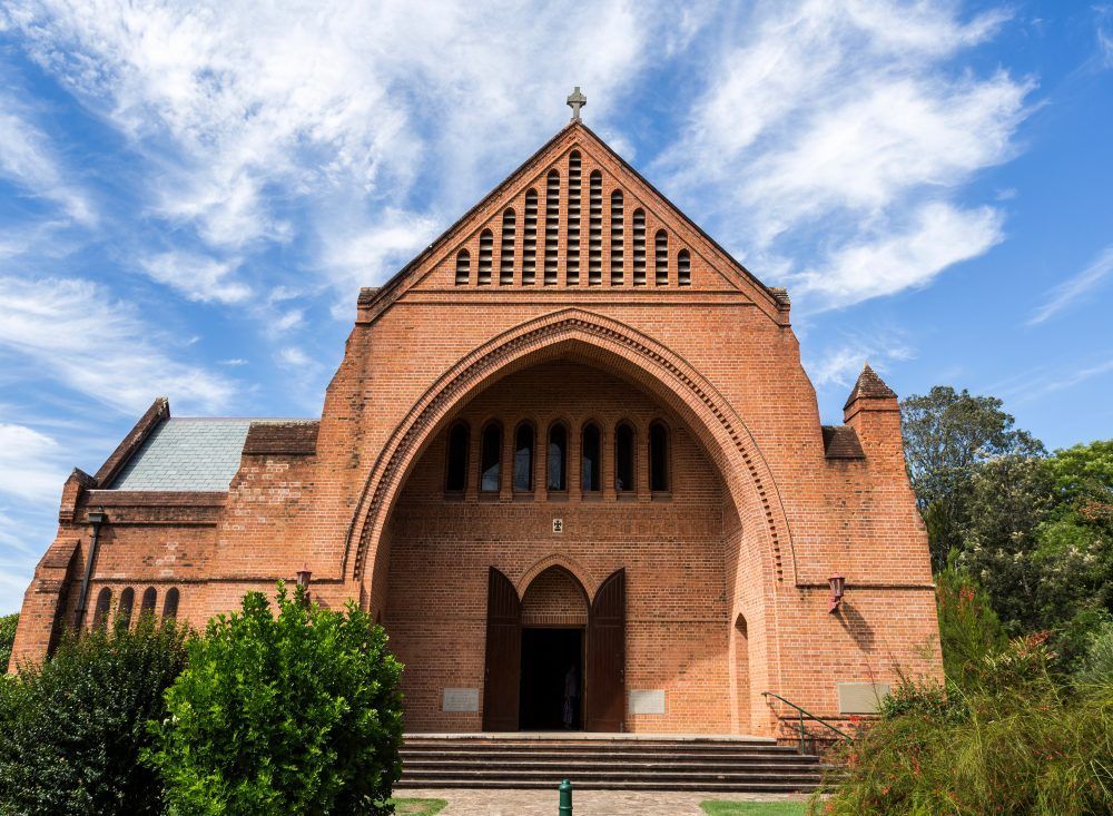A Large Brick Church With a Cross on Top of It — Elite Water In Koonorigan, NSW