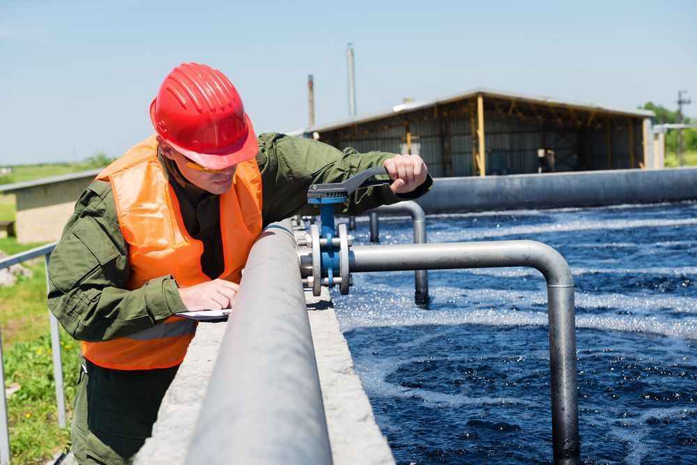 A Man Wearing a Hard Hat is Working on a Pipe — Elite Water In Koonorigan, NSW