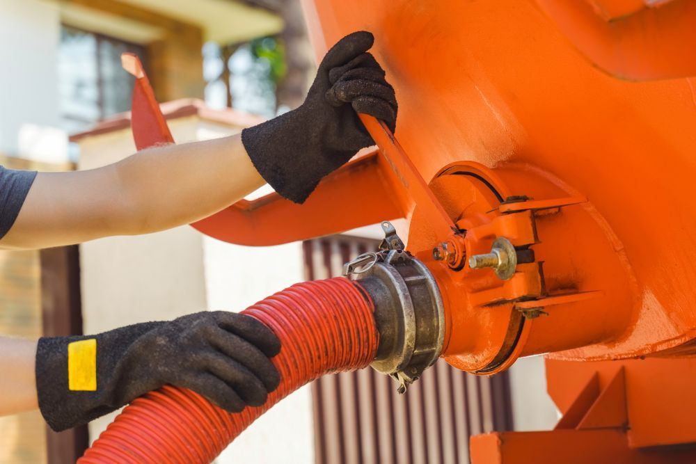 A Man is Holding a Red Hose Attached to an Orange Tank — Elite Water In Casino, NSW