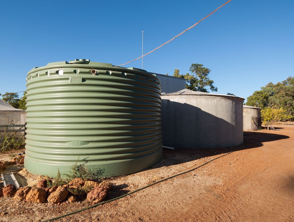 A Row of Water Tanks Are Sitting on Top of a Dirt Road — Elite Water In Grafton, NSW