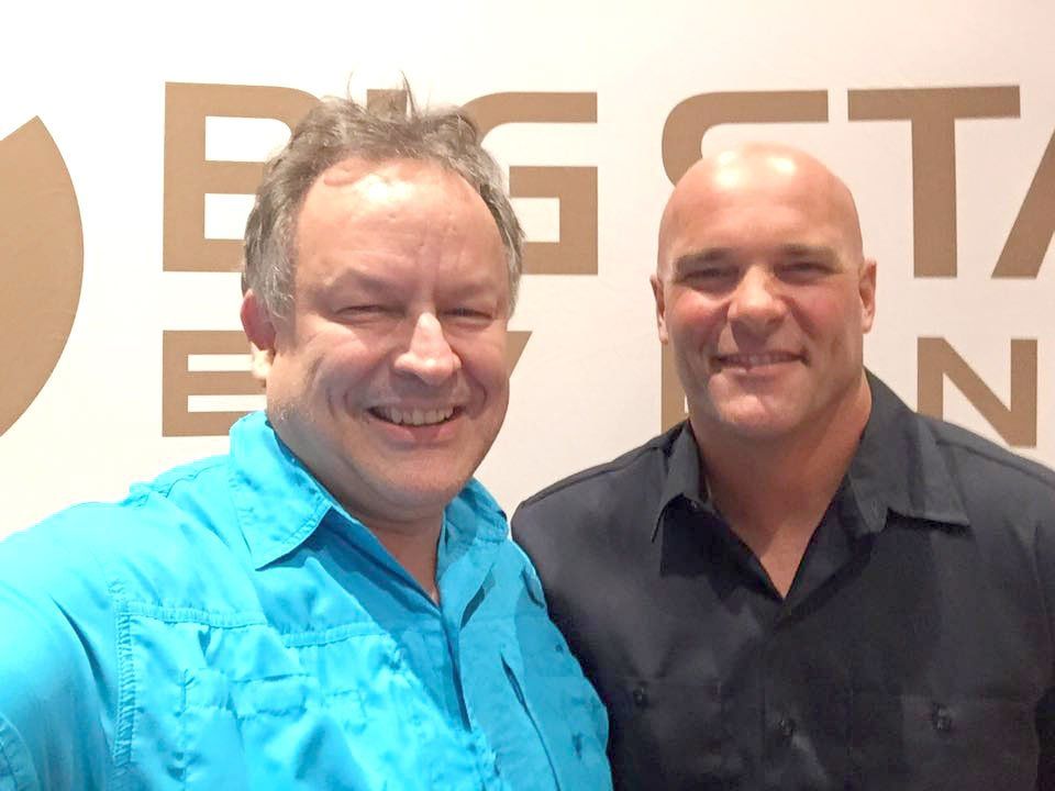 Two men are posing for a picture in front of a big star sign