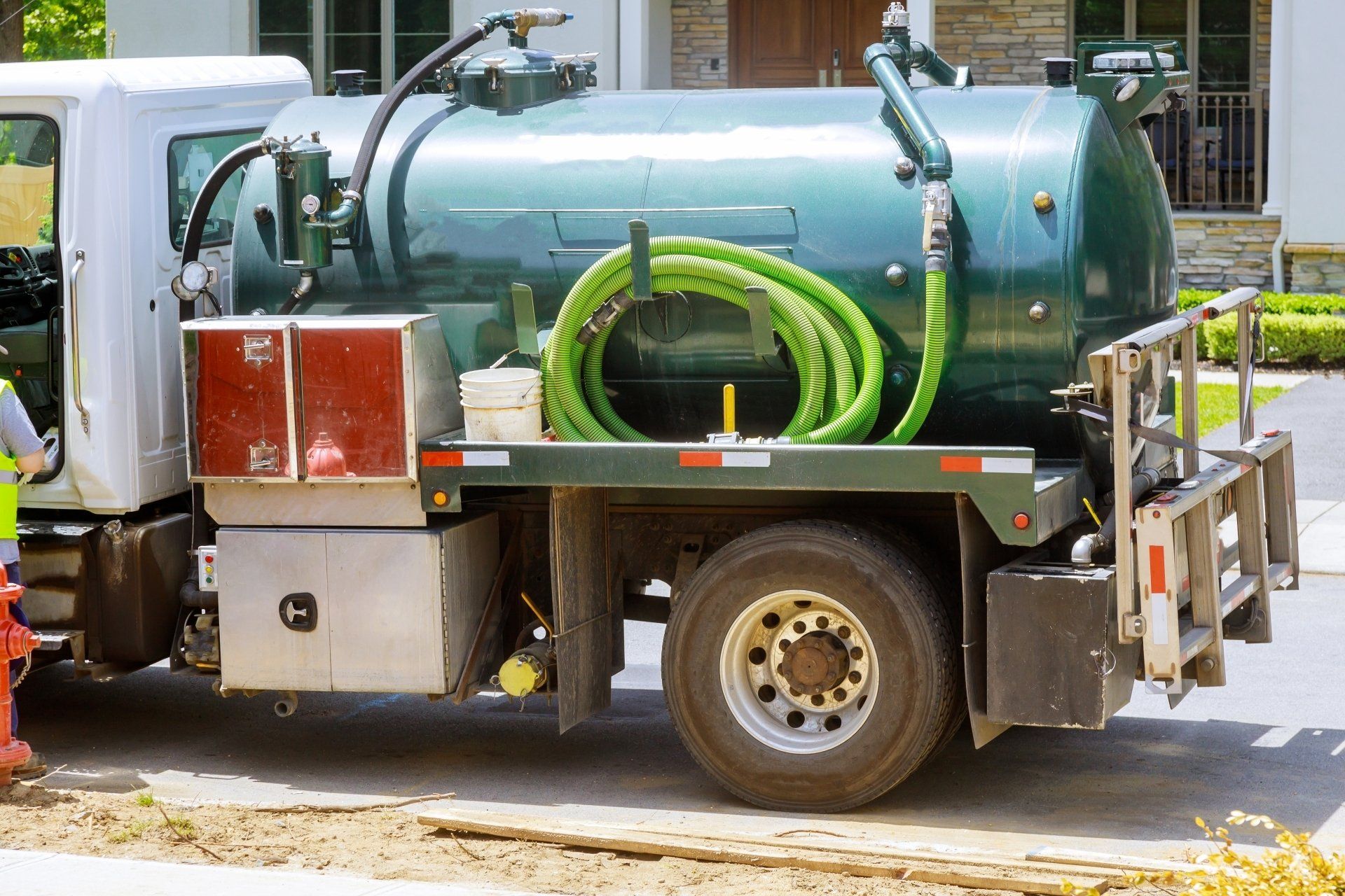 A vacuum truck is parked in front of a house.