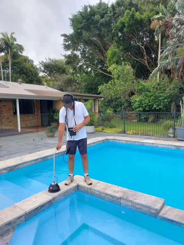 Person using a device to check a pool for leaks outdoors on a cloudy day.