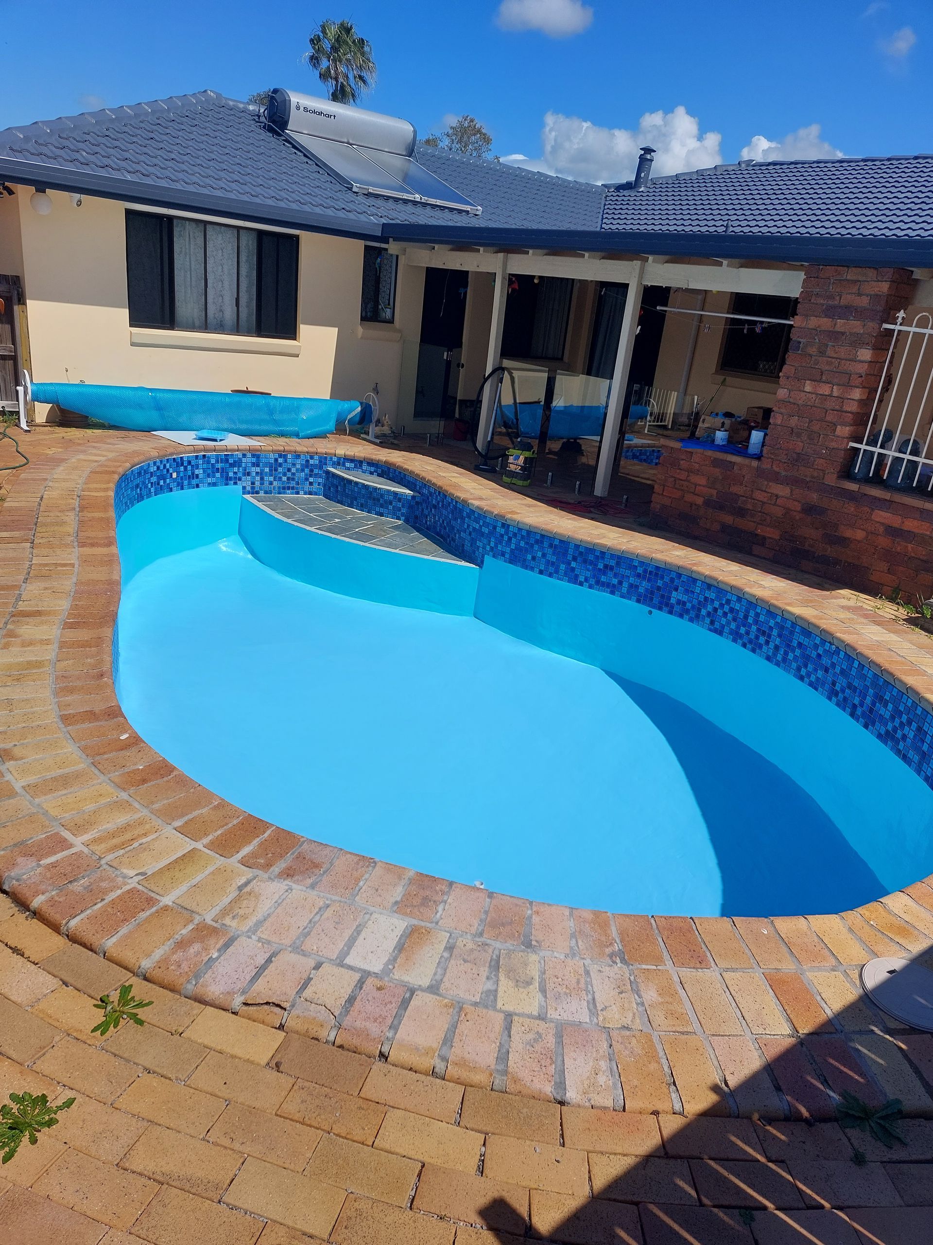 Person Applying Grout to Blue Pool Tiles With a Trowel — Ballina Leak Detection & Swimming Pool Repairs in Ballina, NSW