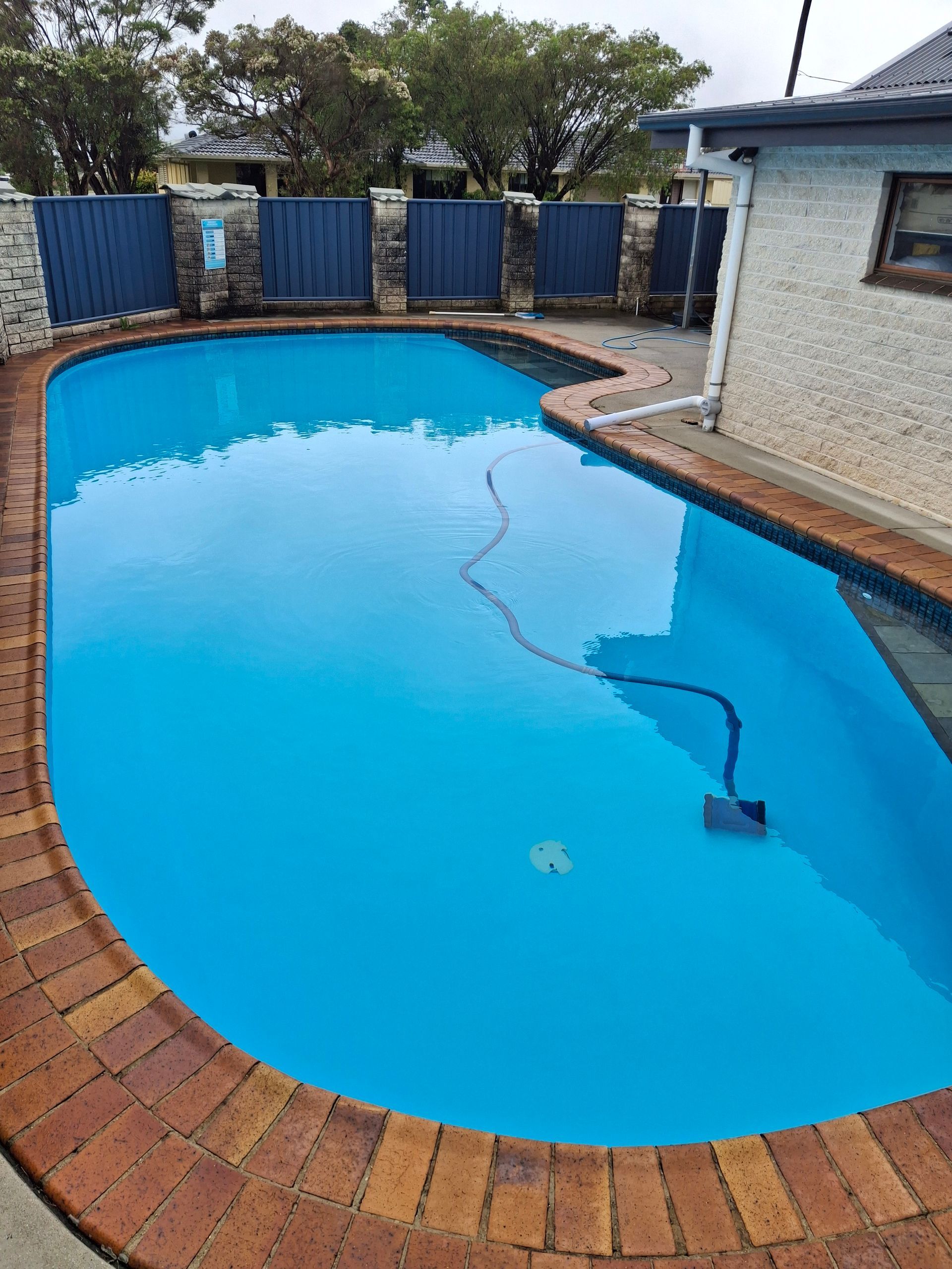 Person Cleaning a Blue Tile Pool With a Brush — Ballina Leak Detection & Swimming Pool Repairs in Byron Bay, NSW
