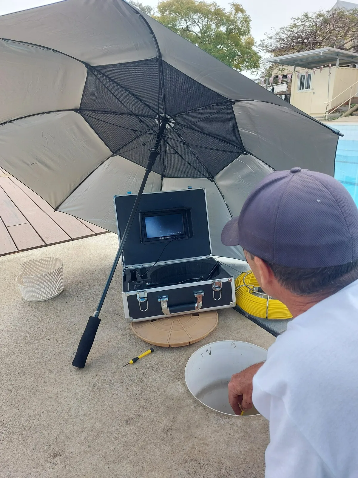 Man Examining Pool Access Point With Equipment — Ballina Leak Detection & Swimming Pool Repairs in Ballina, Nsw