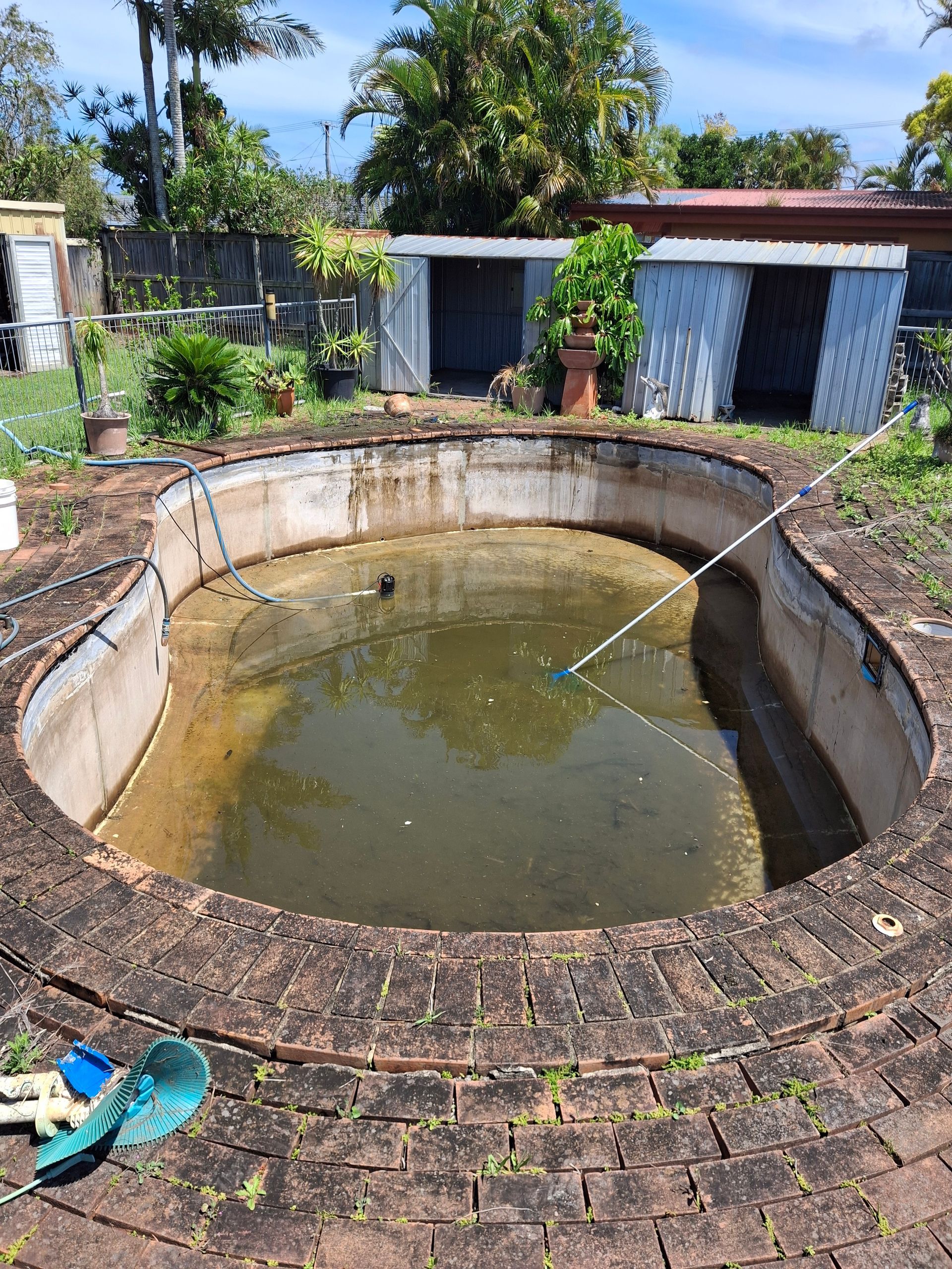 Empty Kidney-shaped Swimming Pool Surrounded by Brickwork — Ballina Leak Detection & Swimming Pool Repairs in Ballina, NSW