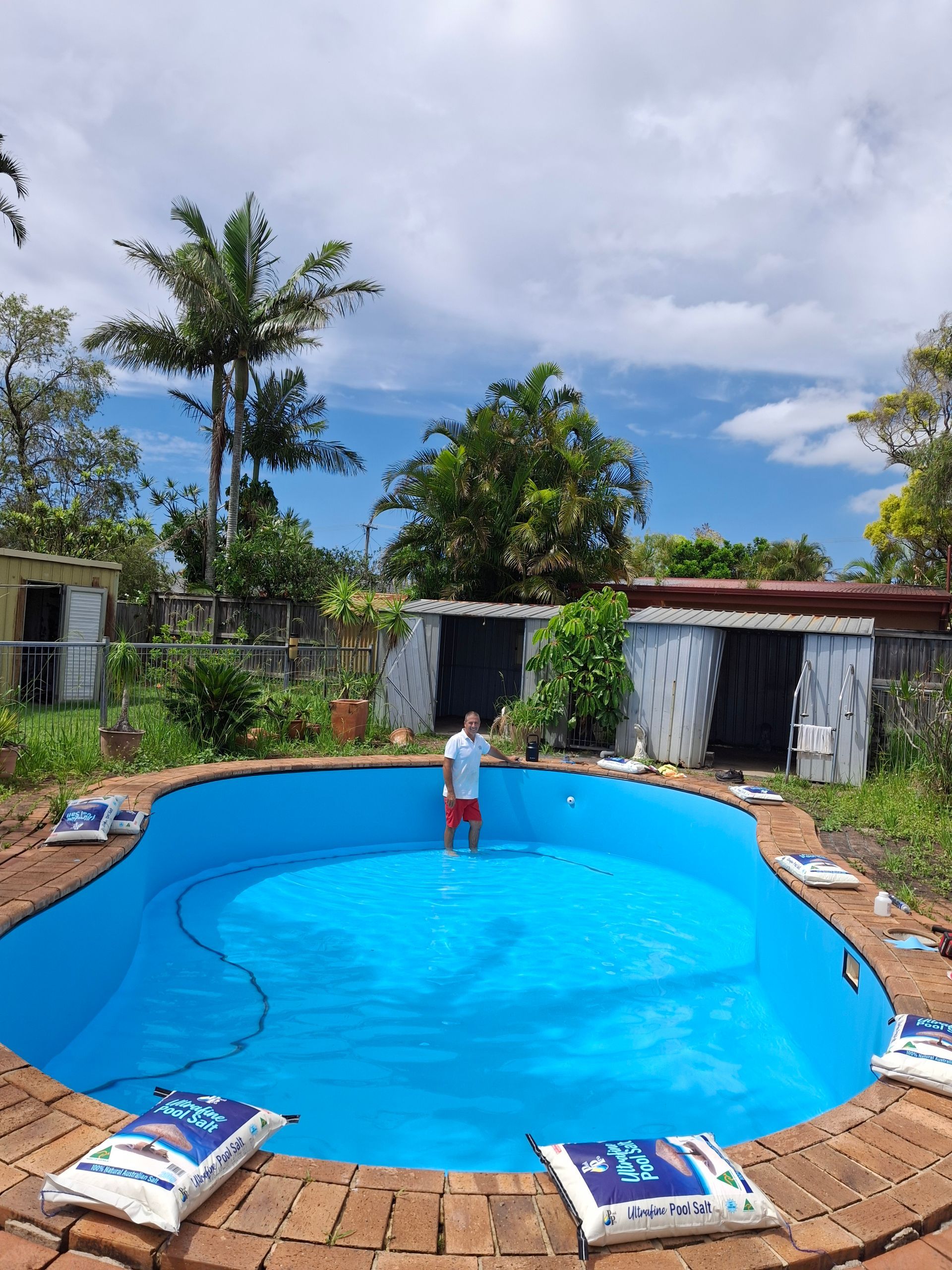 Man Standing in an Empty, Freshly Painted Blue Swimming Pool — Ballina Leak Detection & Swimming Pool Repairs in Ballina, NSW