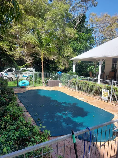 Pool With Blue Cover, Surrounded by Fence and Greenery — Ballina Leak Detection & Swimming Pool Repairs in Ballina, NSW