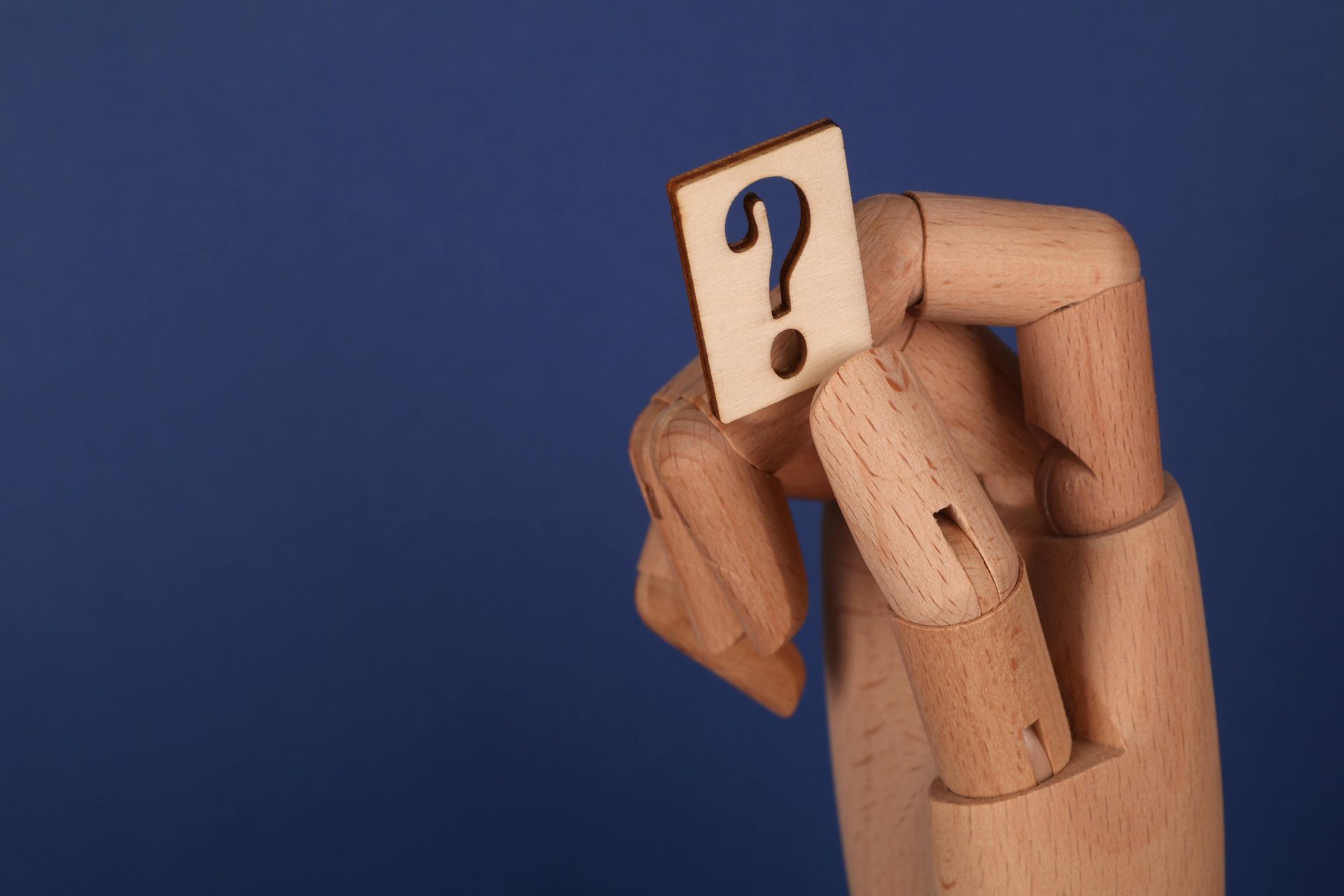 Wooden mannequin with a question mark on its face against a blue background