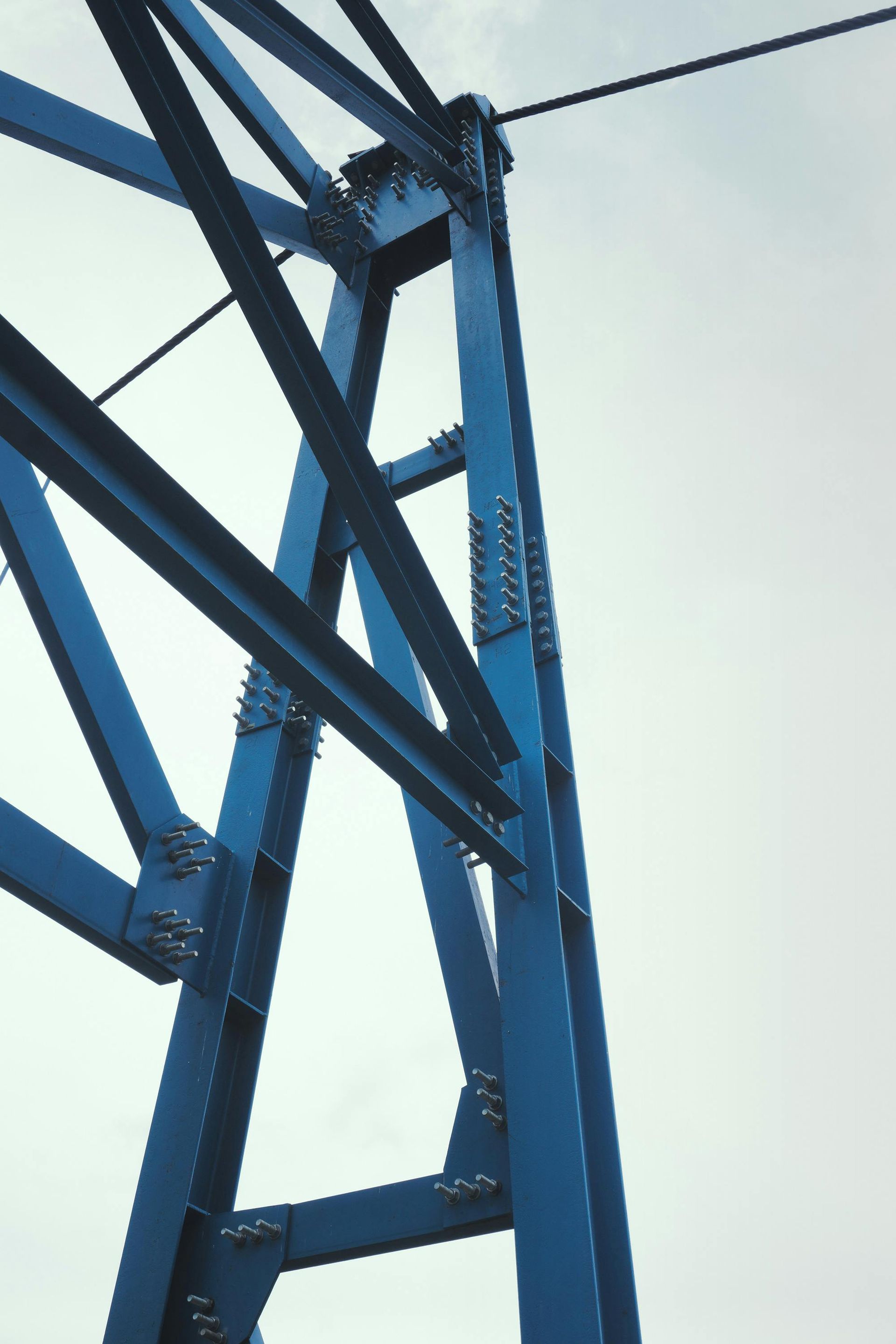 Blue steel bridge structure against a cloudy sky