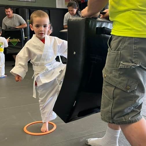 A young girl is practicing taekwondo in a gym.