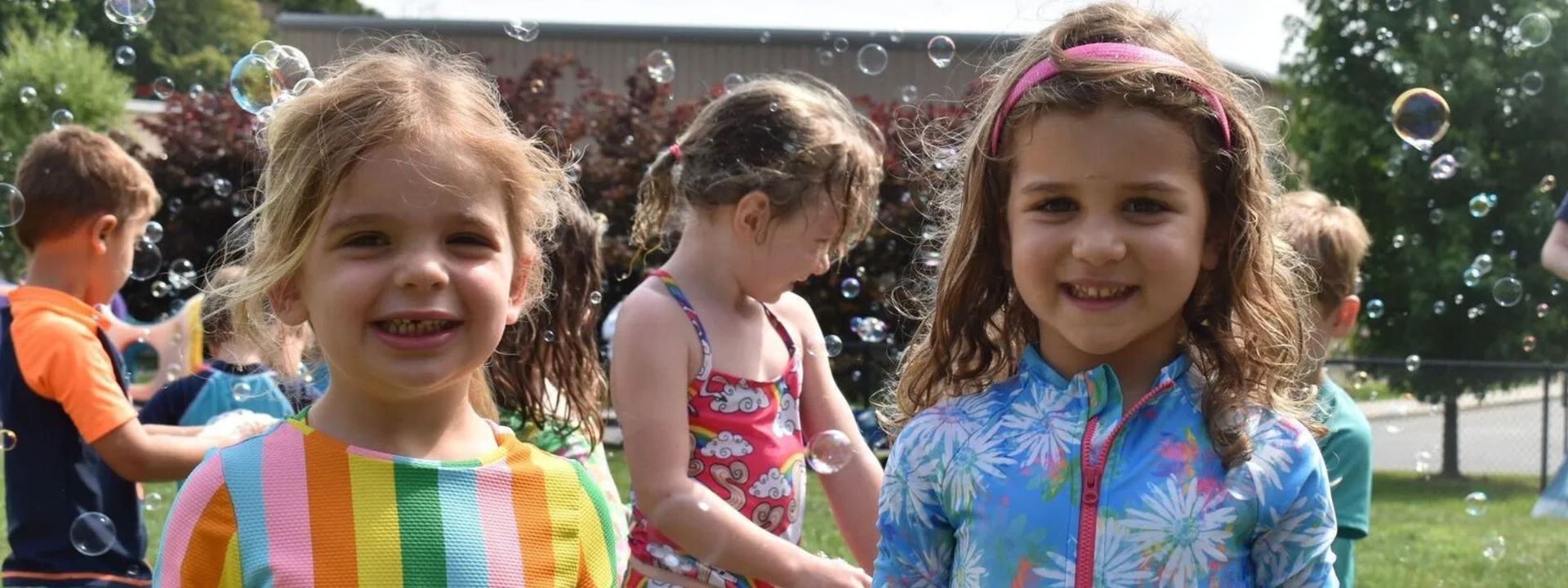 Two little girls are standing next to each other in a park.