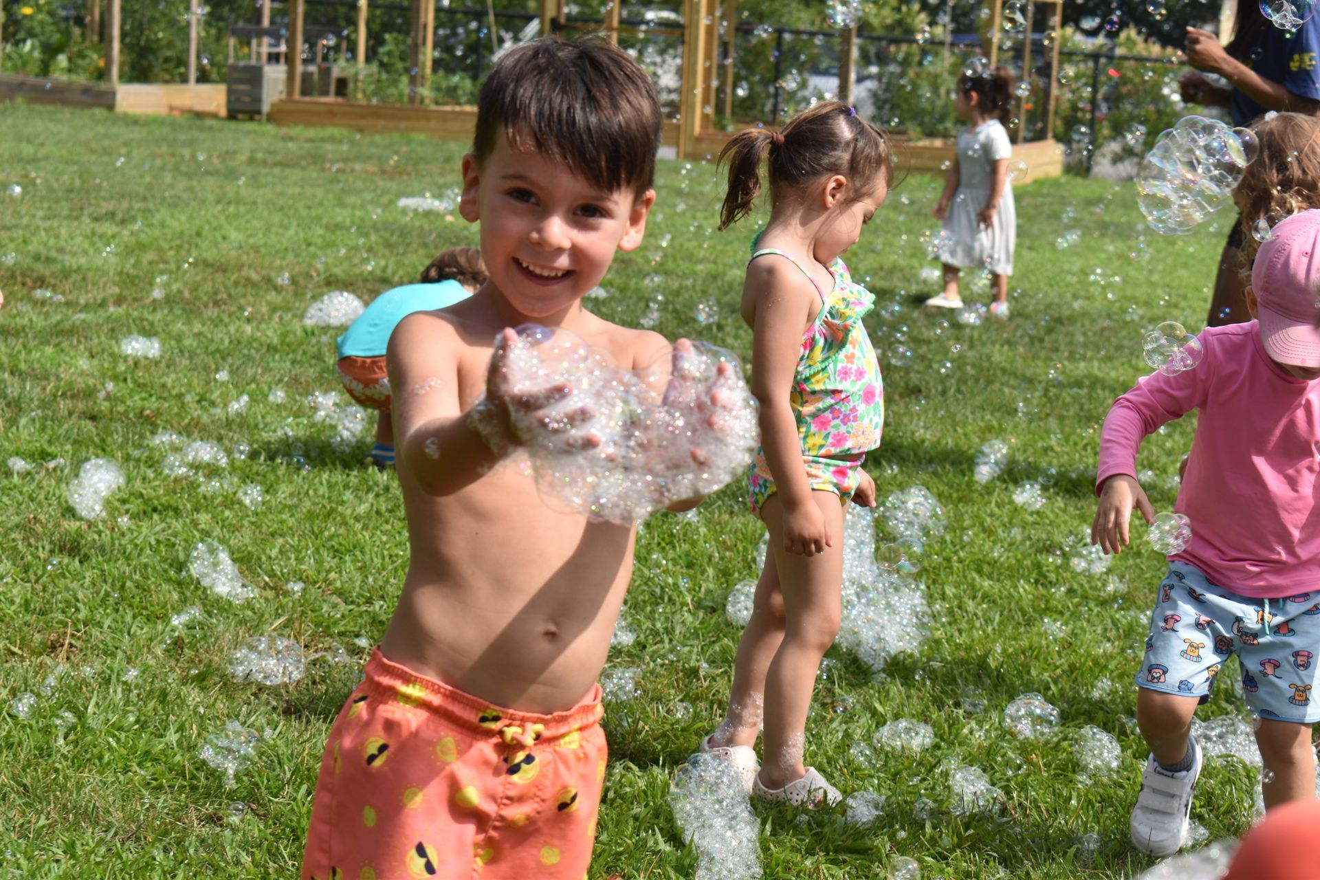 A group of children are playing with soap bubbles in a park.