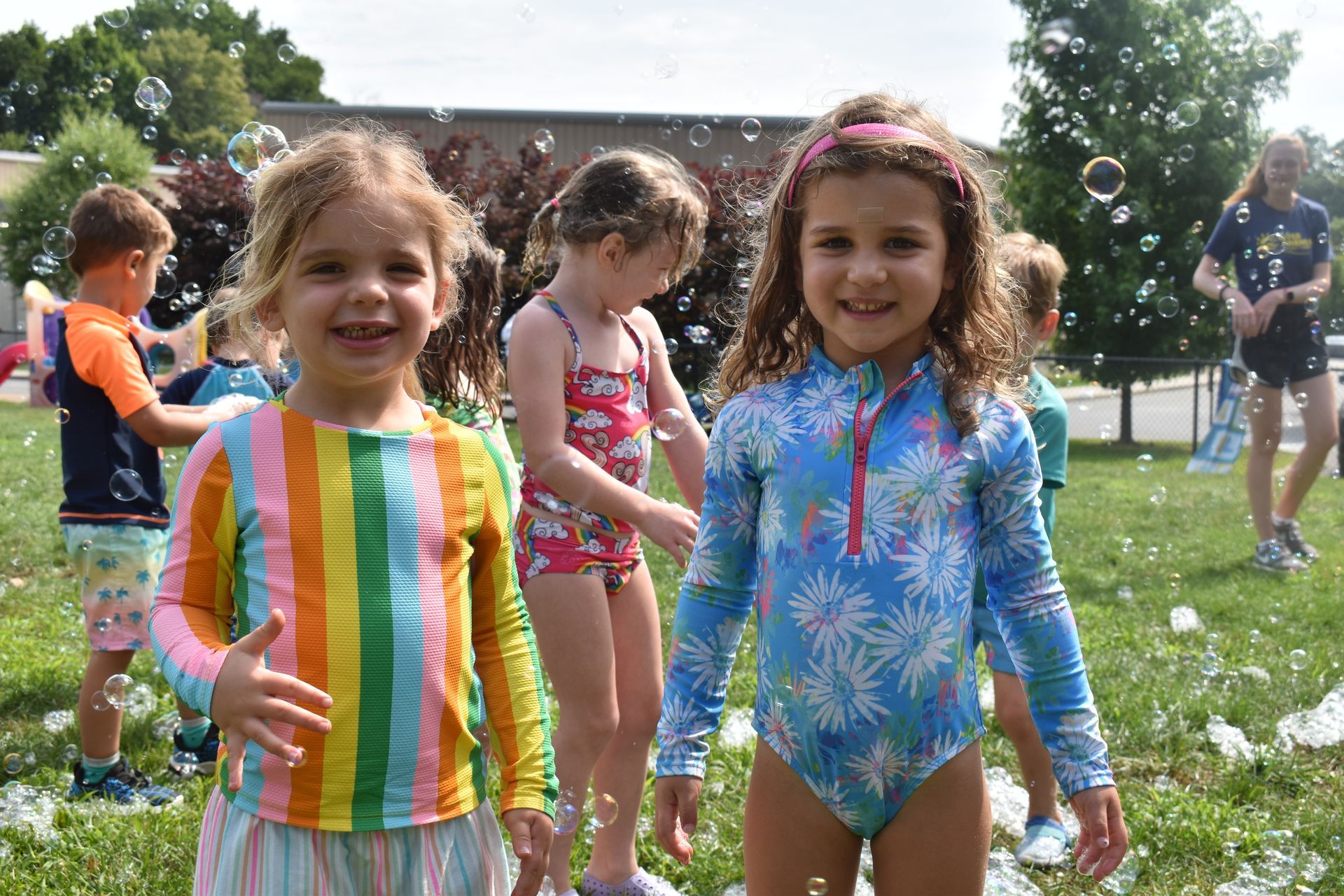 A group of young girls are playing with soap bubbles in a park.