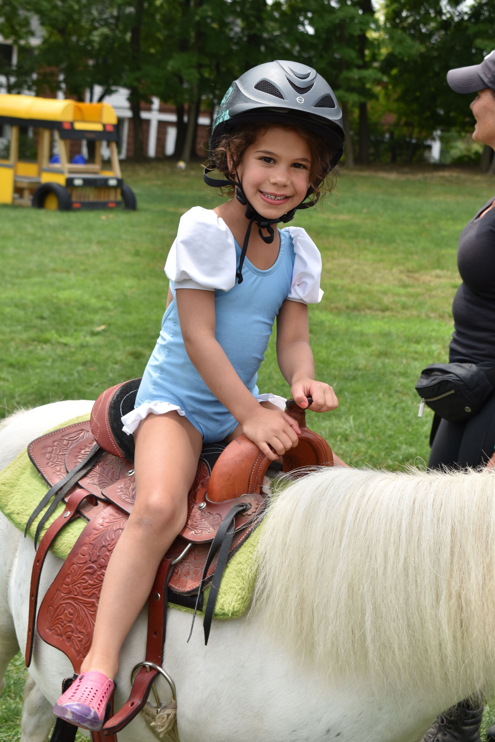 A little girl wearing a helmet is riding a pony