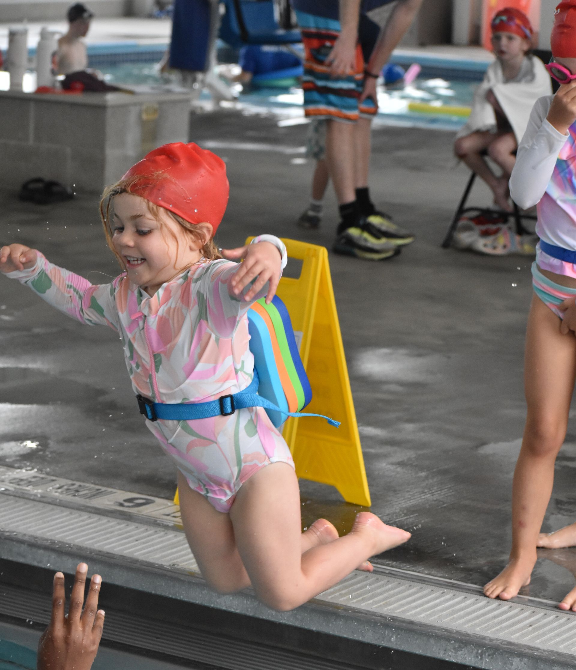 A little girl is jumping into a swimming pool