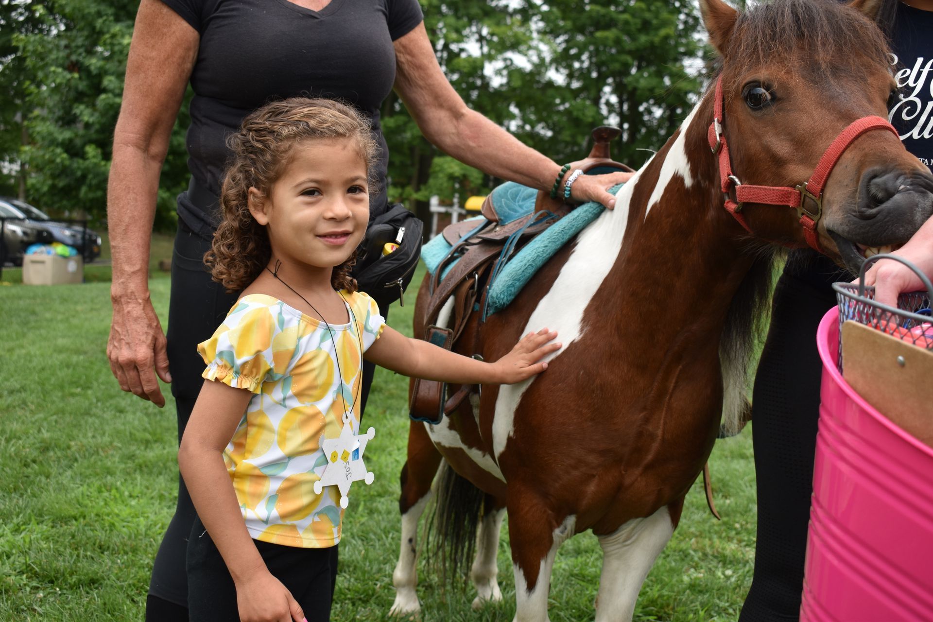 A little girl is petting a brown and white pony.