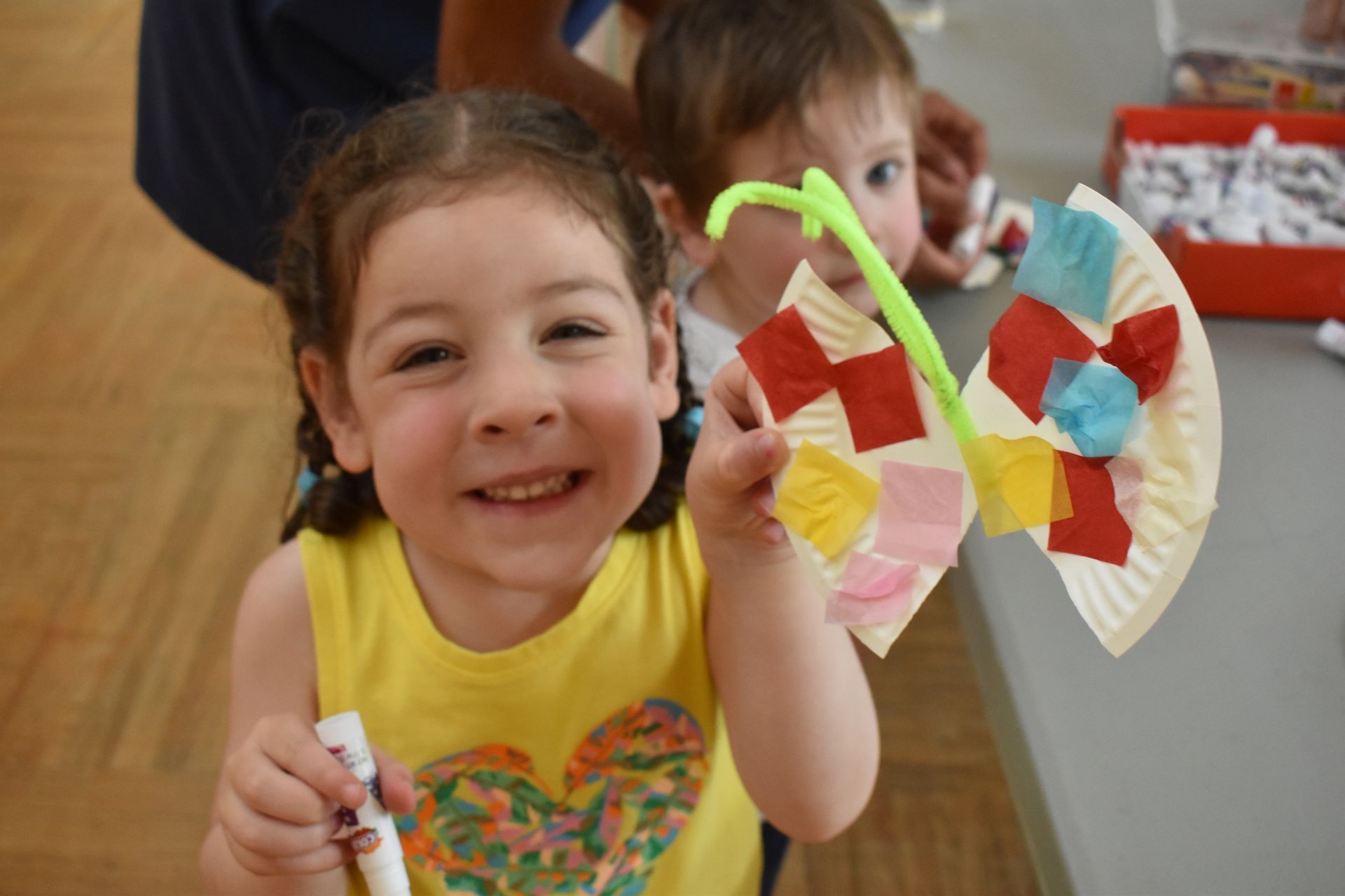 A little girl is holding a butterfly made out of paper plates.
